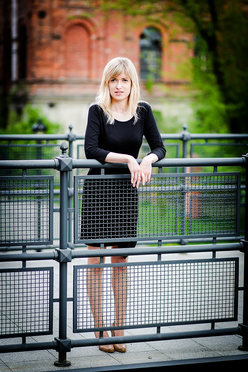 Sesja Modowa Księży Młyn: Modelka w czarnej sukience na tle cegły.