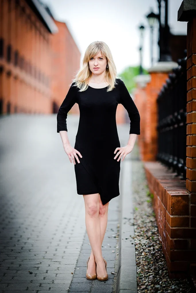 Sesja Modowa Księży Młyn: Modelka w czarnej sukience na tle cegły.