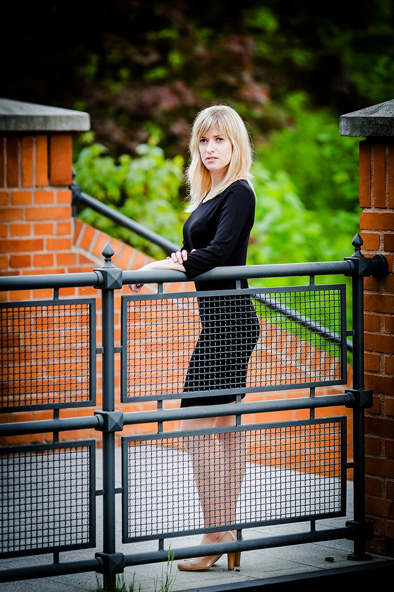 Sesja Modowa Księży Młyn: Modelka w czarnej sukience na tle cegły.