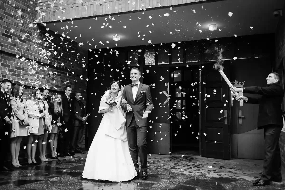 Fotografia przedstawiająca młodą parę wychodzącą z kościoła z konfetti nad nimi Łódź fotograf